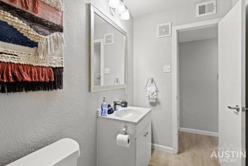 ein weißes Badezimmer mit einem Waschbecken und einem Spiegel in der Unterkunft Pet Friendly w Pool Near Mueller Free Parking in Austin