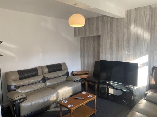 a living room with a leather couch and a flat screen tv at Ratcliffe House - Spacious 3 bedroom House in Sileby in Sileby