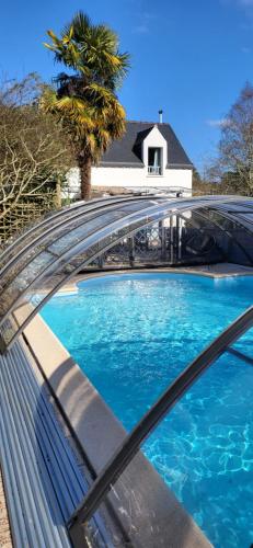 una piscina con techo de cristal y una casa en Gite Kergroix en Carnac en Carnac