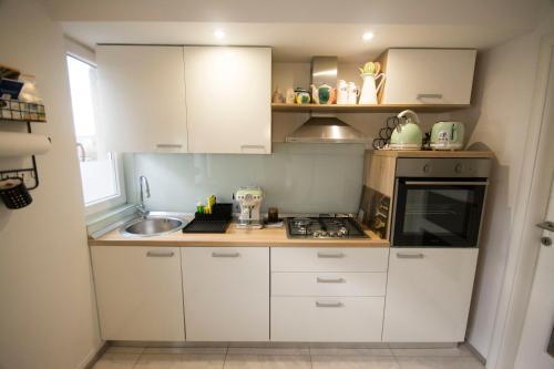 una pequeña cocina con armarios blancos y fregadero en Apartman Lipa en Slavonski Brod