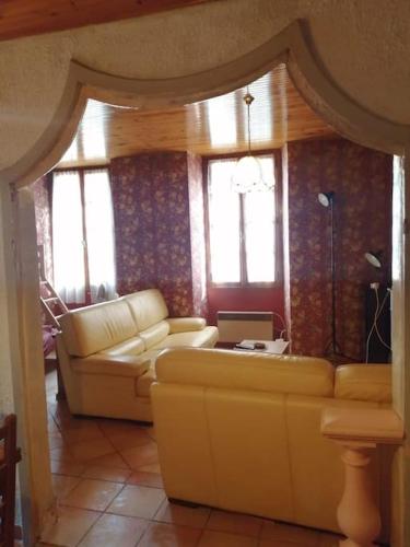 een woonkamer met een bank, een tafel en ramen bij Sospel cœur de village in Sospel