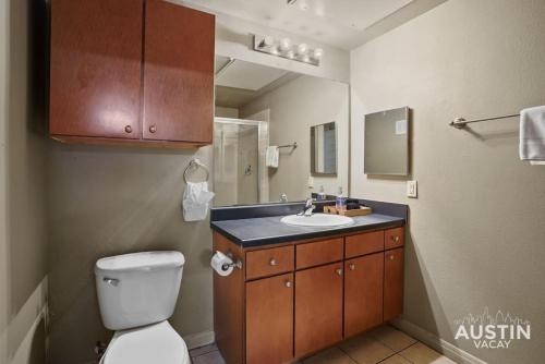 a bathroom with a toilet and a sink and a mirror at Balcony Views and Ideal West Campus Austin Location in Austin