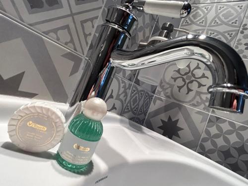 a green bottle of soap in a bathroom sink at Demeure du Vallon - Chambres d'Hôtes de Charme in Azerat