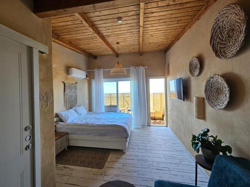 um quarto com uma cama e uma grande janela em בריאה אירוח בטבע em Sha'al