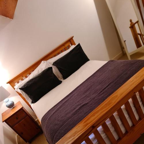 a bedroom with a wooden bed with black pillows at Newditch Farm - BRS Airport in Bristol