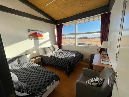 Habitación con 2 camas, sofá y ventana en Godaland Guesthouse and Glamping, en Hlíðarendi