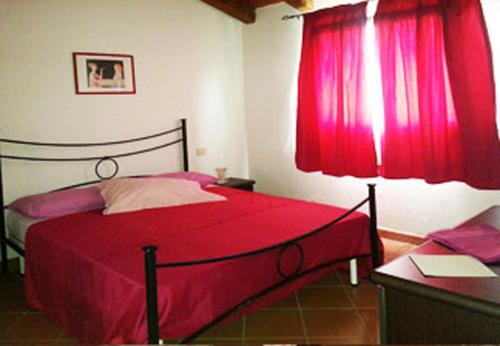 een slaapkamer met een rood bed en rode gordijnen bij Villa Aura in Stintino