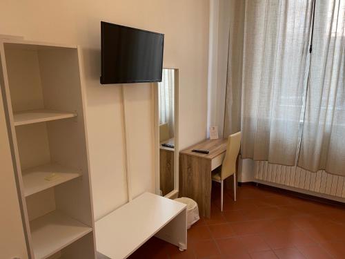 Habitación pequeña con escritorio y TV en la pared. en Downtown - Camere in Centro, en Ferrara