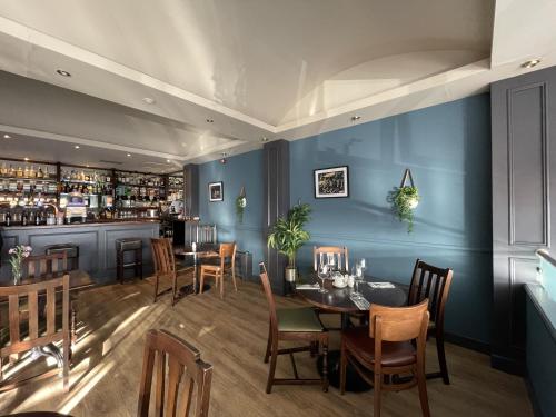 a dining room with blue walls and tables and a bar at The Ferry Inn in Thurso