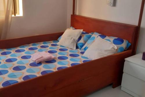 Bett mit einem Kopfteil aus Holz und Kissen darauf in der Unterkunft Maison individuelle cozy à OUEDO cotonou 