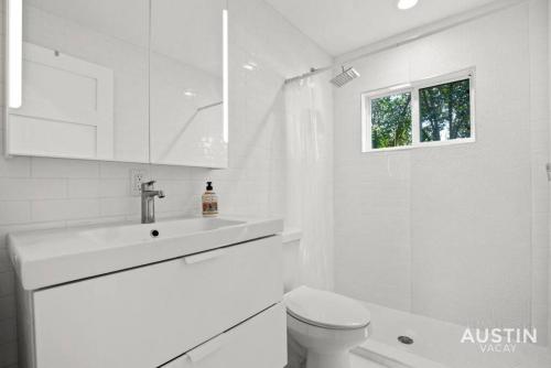 a white bathroom with a toilet and a sink at Walk to UT and E 6th in Fully Equipped ATX House in Austin