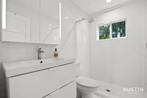 a white bathroom with a toilet and a sink at Walk to UT and E 6th in ATX House and Free Swim Club by Austin Vacay in Austin