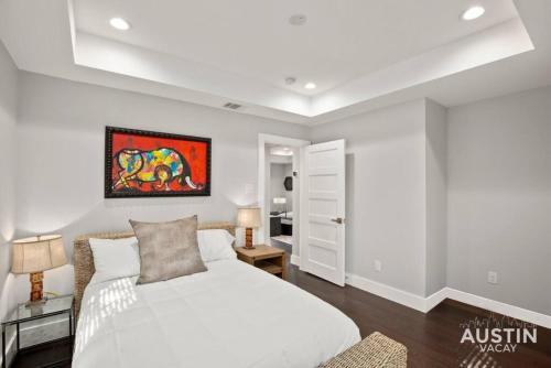 a bedroom with a white bed and a painting on the wall at Walk to UT and E 6th in ATX House and Free Swim Club by Austin Vacay in Austin
