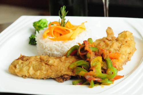 a plate of food with rice and chicken and vegetables at Addissinia Hotel in Addis Ababa