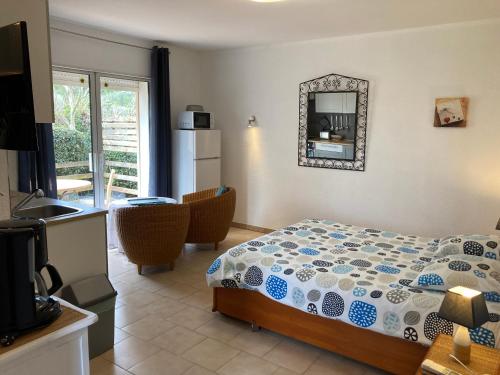 ein Schlafzimmer mit einem Bett und einem Spiegel sowie eine Küche in der Unterkunft Les Bougainvillées de Camargue in Villetelle
