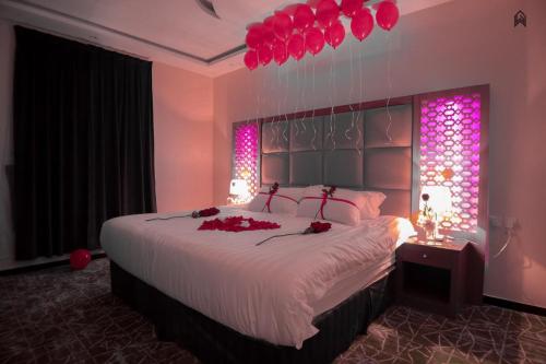 a bedroom with a large bed with red flowers on it at Loluat Al Matar Furnished Units in Jazan