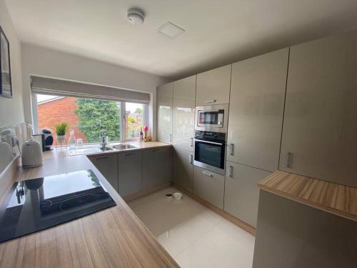 a large kitchen with white cabinets and a window at HOME from HOME in Birmingham