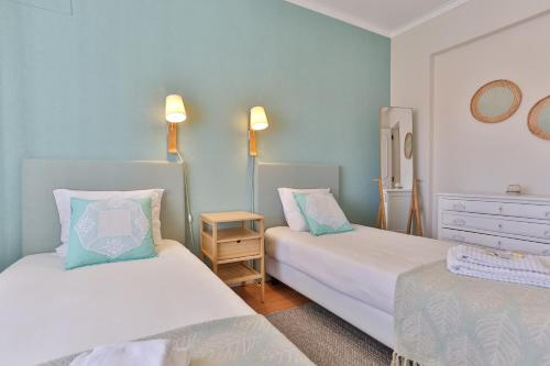 two beds in a room with blue walls at Caparica Sun Beach Villa in Charneca