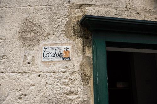 a sign on the side of a stone building with a window at Residence Le Vie Del Mosto in Matera