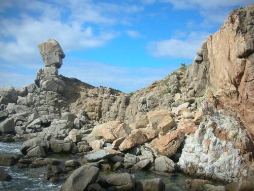 a rocky mountain with a statue on top of it at Mare & Mirice - Case Appartamenti Vacanza in Aglientu