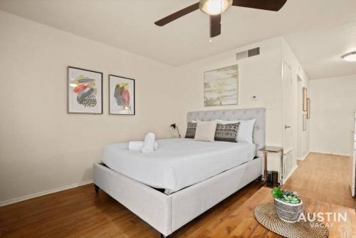 a bedroom with a large white bed with a ceiling fan at Relax in Hyde Park Parking Great Location and Tub in Austin
