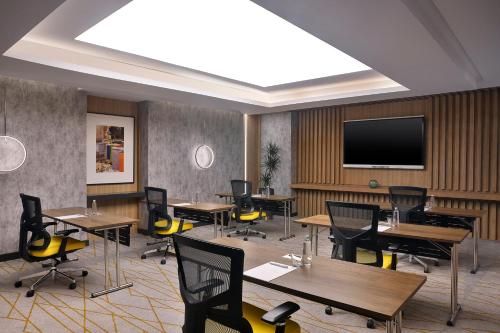 a conference room with tables and chairs and a flat screen tv at Holiday Inn & Suites - Al Khobar by IHG in Al Khobar