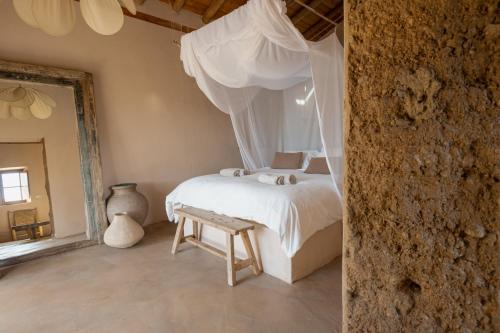 - une chambre avec un lit avec des rideaux et un banc dans l'établissement The Lemon Lodge, à Aljezur