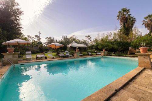 uma grande piscina azul com cadeiras e guarda-sóis em La Baronia em Trapani