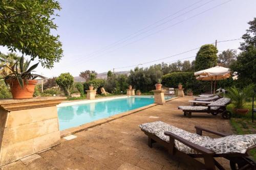 ein Pool mit zwei Bänken und einem Sonnenschirm in der Unterkunft La Baronia in Trapani