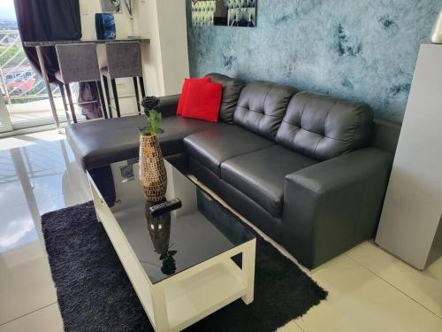 a living room with a leather couch and a table at Sheryll Escapes - Kandi Tower 3 premium loft 1BR on 8th floor with 2CR & 2 balconies in Angeles
