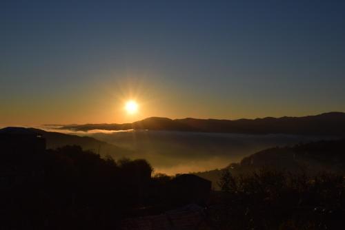 a sunset with the sun rising over a fog covered valley at Taniq Guesthouse in Artsvaberd