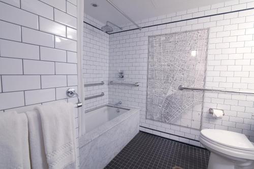 La salle de bains blanche est pourvue d'une baignoire et de toilettes. dans l'établissement The Frederick Hotel Tribeca, à New York