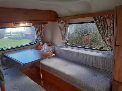 Habitación pequeña con mesa y 2 ventanas en Sundial Cottage Eriba Caravan en Norwich