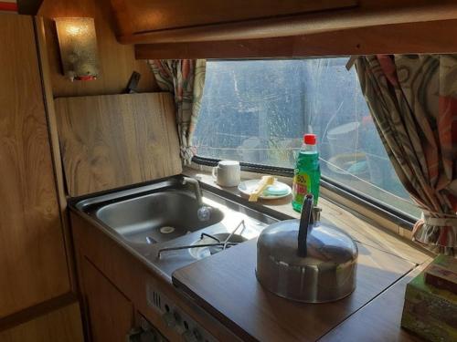 a kitchen with a sink and a stove and a window at Sundial Cottage Eriba Caravan in Norwich