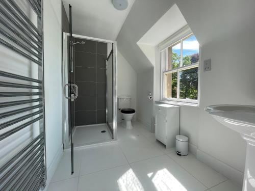 a white bathroom with a shower and a toilet at Balloan House in Dornoch