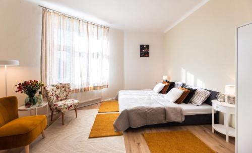 a bedroom with a bed and a chair and a window at Silvie Apartments - Šmeralova in Olomouc