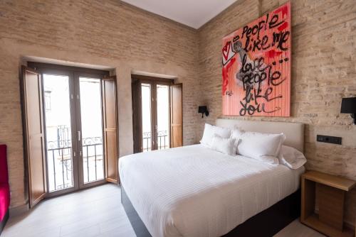 Un dormitorio con una cama blanca y una pintura en la pared en Casa ART Sevilla, en Sevilla