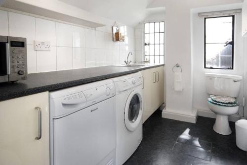 a white kitchen with a washing machine and a toilet at Charming Cottage in the Heart of Frome with parking in Frome