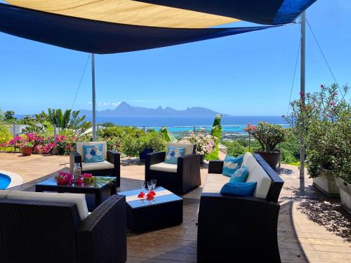 a patio with chairs and tables and an umbrella at Villa Green in Punaauia