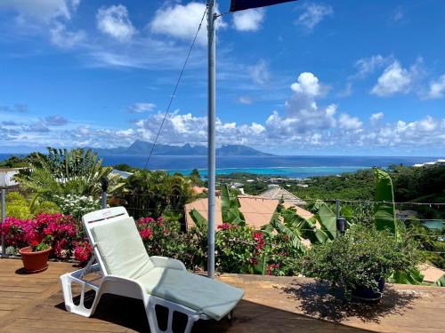 une chaise blanche assise sur une terrasse avec vue sur l'océan dans l'établissement Villa Green, à Punaauia