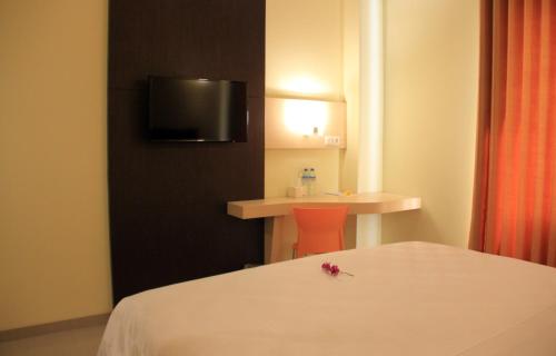 a hotel room with a bed and a table and a tv at M Hotel in Mataram