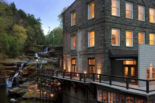 a stone house with a waterfall in the background at Peaceful Seasonal Wooded Cottage close to everything in Tafton