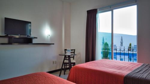 Habitación de hotel con 2 camas y ventana grande. en Hotel Osalle Inn, en Chignahuapan
