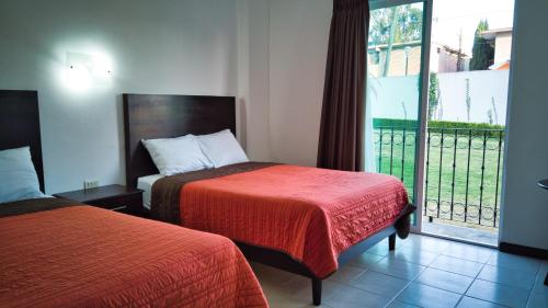 a hotel room with two beds and a balcony at Hotel Osalle Inn in Chignahuapan