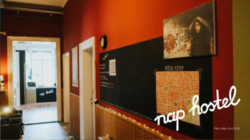 a hallway with a red wall with a sign on it at Nap Hostel Pécs in Pécs