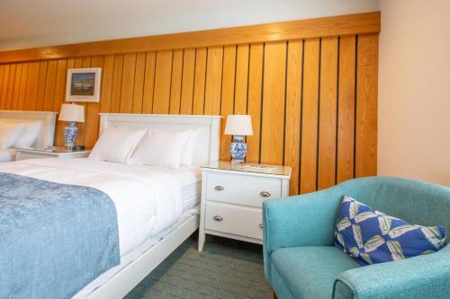 a bedroom with a bed and a blue chair at The Leland Lodge in Leland