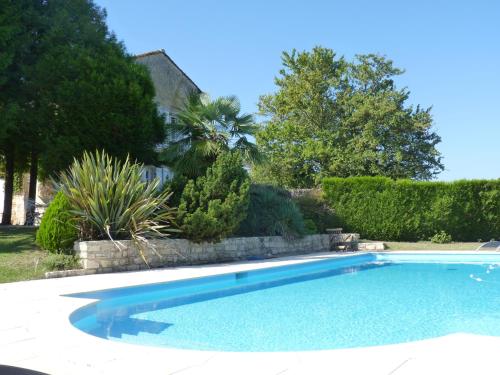 - une piscine dans une cour avec des arbres et des buissons dans l'établissement Domaine du Champ Fleuri, à Angoulême