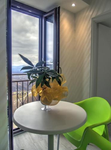 a table with a plant and two green chairs at B&B Il Belvedere Viggiano in Viggiano