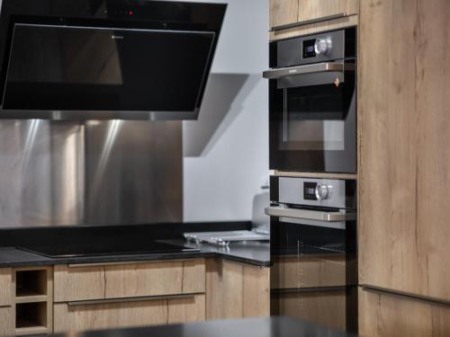 Il comprend une cuisine équipée d'un four avec plaques de cuisson noires. dans l'établissement Charmant Appartement Pistes Courchevel - 78m², 8 Pers., WiFi, Parking, Services Inclus - FR-1-563-43, à Courchevel