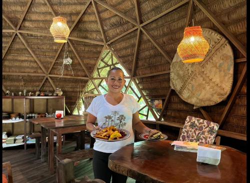 una mujer sosteniendo un plato de comida en una cabaña en Palmayacu - Refugio Amazónico, en Leticia